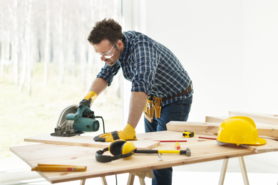 carpenter cutting plank by circular saw